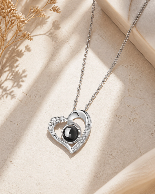 Crystal Heart photo projection necklace laying on cream stone
