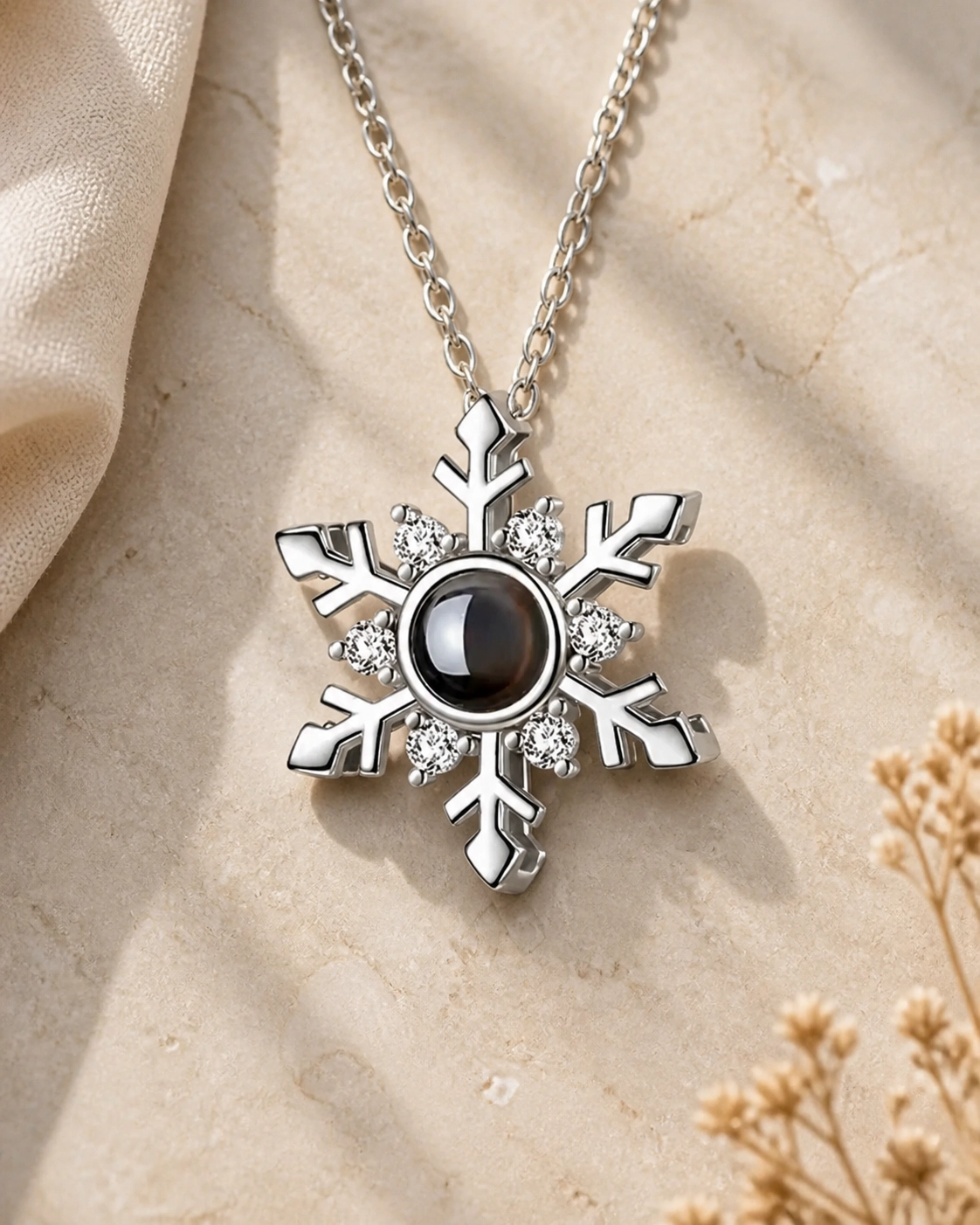 Icy Snow snowflake photo projection necklace laying on cream stone