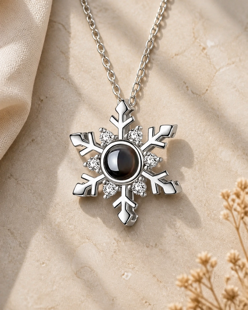 Icy Snow snowflake photo projection necklace laying on cream stone