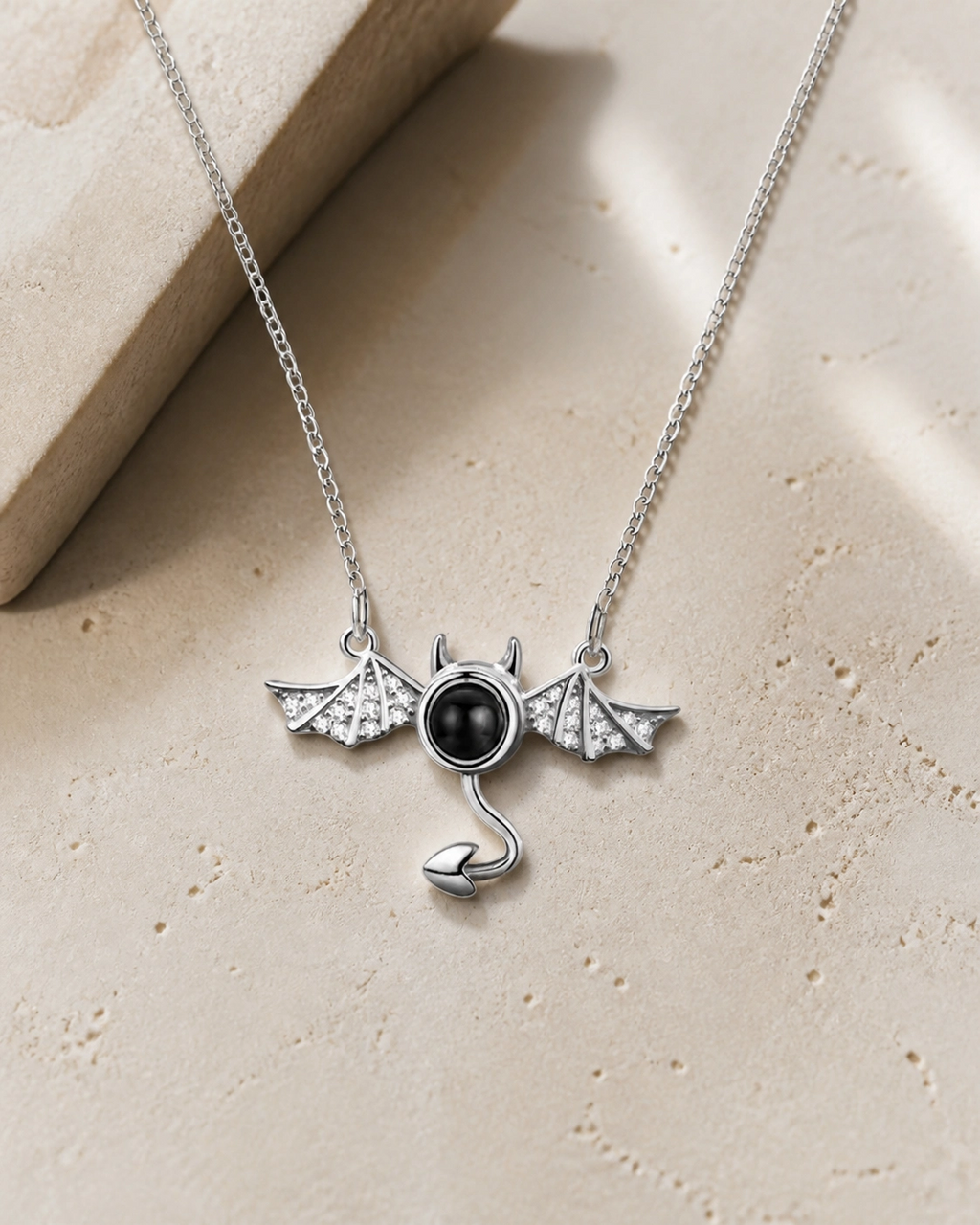 Little Devil photo projection necklace laying on cream stone