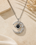 Moonshine moon and sun photo projection necklace laying on cream stone
