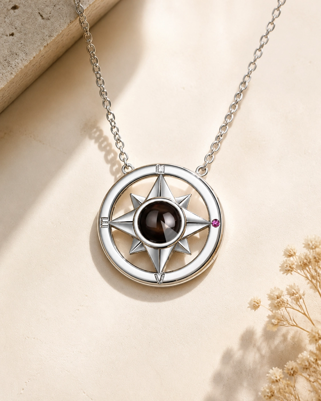 Northern Star compass photo projection necklace laying on cream stone