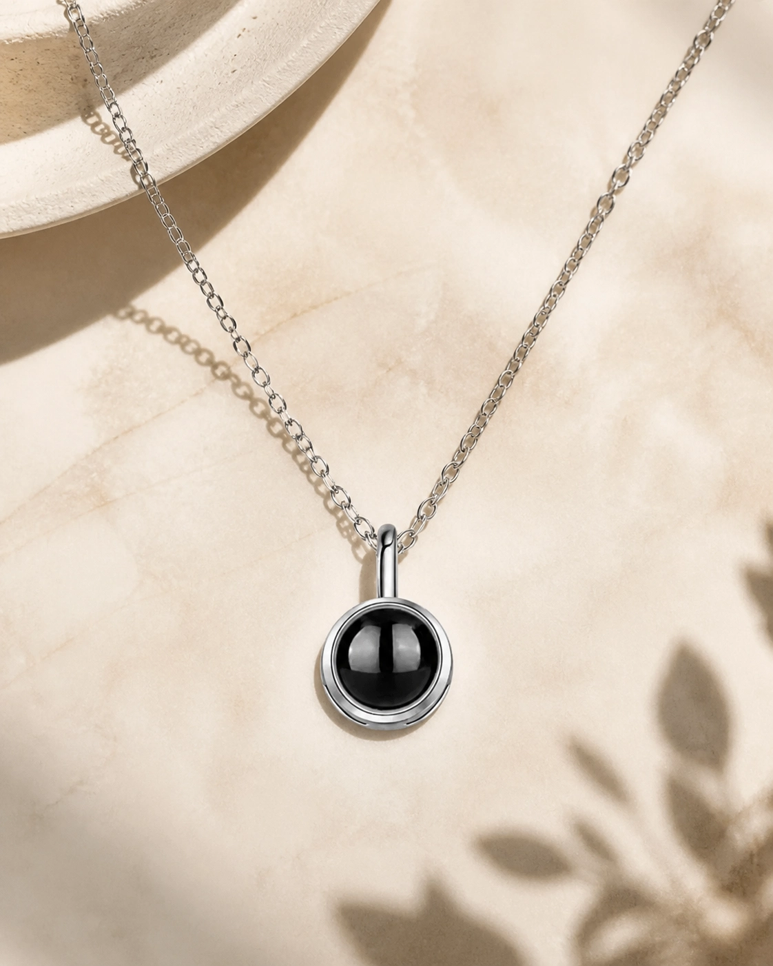 The Classic photo projection necklace laying on cream stone